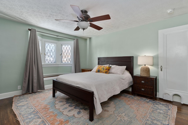 bedroom featuring a textured ceiling, dark wood finished floors, a ceiling fan, and baseboards