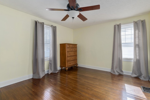 unfurnished room featuring dark wood-style floors, baseboards, visible vents, and a textured ceiling