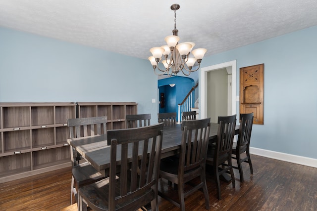 dining room with arched walkways, dark wood-style flooring, a textured ceiling, a chandelier, and baseboards