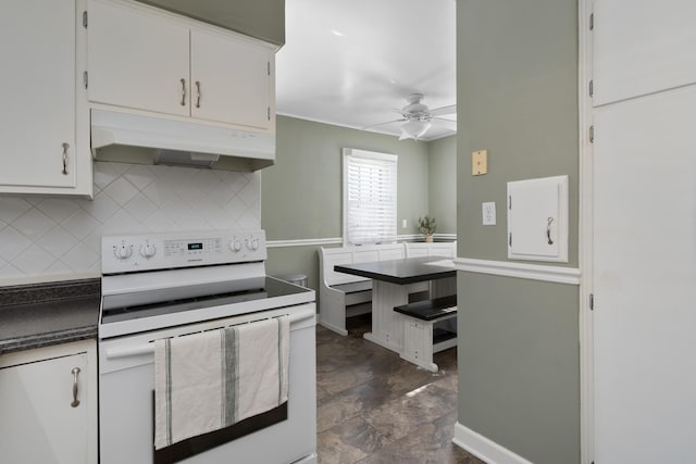 kitchen with electric stove, tasteful backsplash, dark countertops, white cabinets, and under cabinet range hood