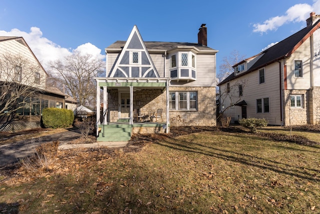 back of property featuring a porch, stone siding, a lawn, and a chimney