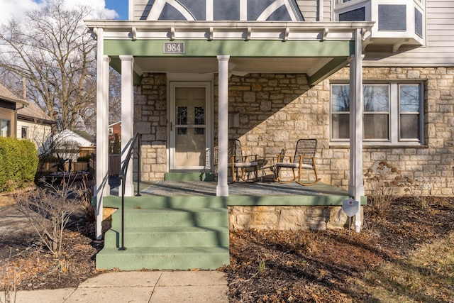 doorway to property featuring covered porch and stone siding