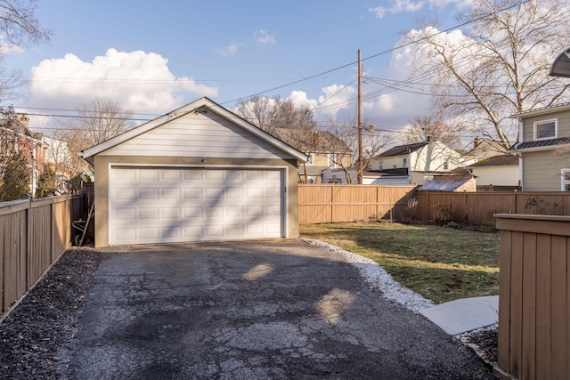 detached garage featuring aphalt driveway and fence