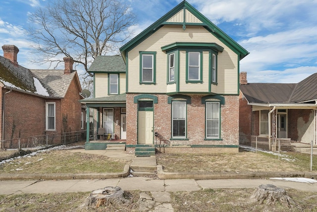 victorian house with a porch, fence, and brick siding