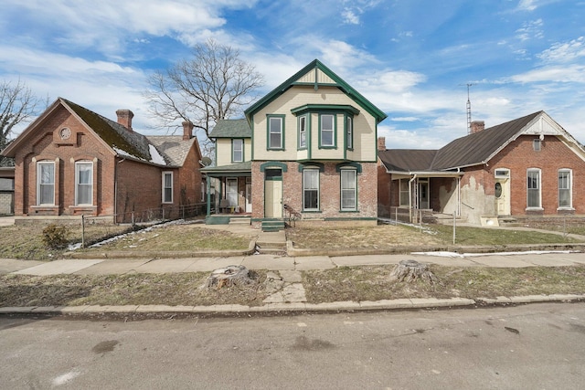 victorian home featuring covered porch and brick siding