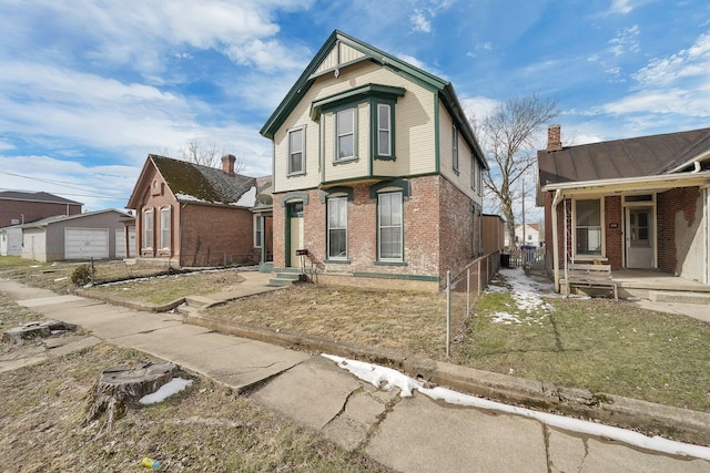 view of front of house featuring brick siding, a standing seam roof, a detached garage, and a front yard