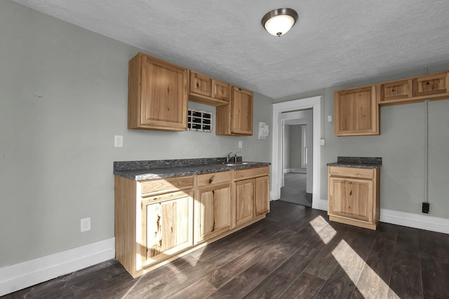 kitchen with dark countertops, dark wood-style floors, baseboards, and a textured ceiling