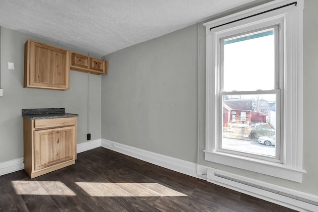 unfurnished dining area with baseboards, a baseboard heating unit, dark wood finished floors, and a textured ceiling