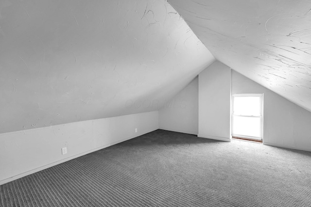 bonus room with vaulted ceiling and carpet