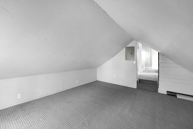 bonus room with vaulted ceiling, electric panel, dark carpet, and baseboards