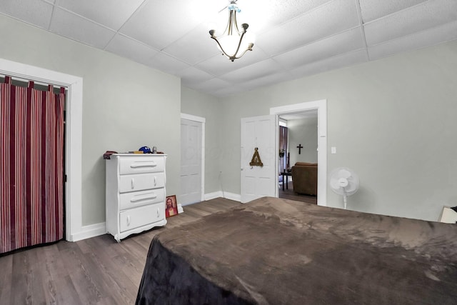 bedroom with a drop ceiling, dark wood finished floors, and baseboards