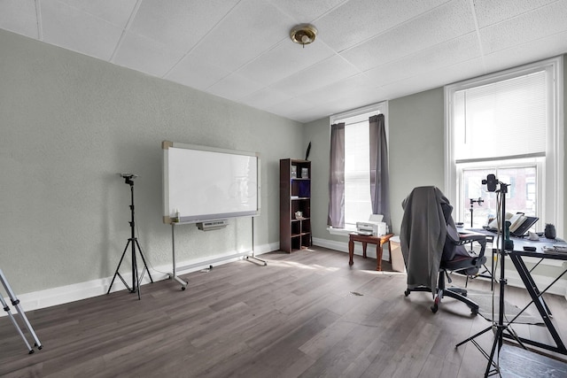 office featuring a textured wall, baseboards, and wood finished floors