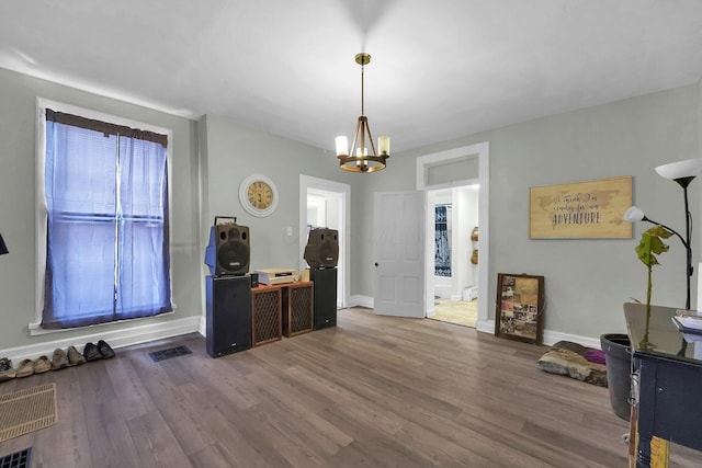 office space featuring baseboards, wood finished floors, visible vents, and an inviting chandelier