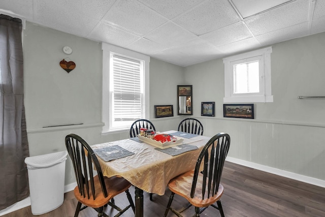 dining space featuring dark wood-type flooring, wainscoting, a paneled ceiling, and baseboards