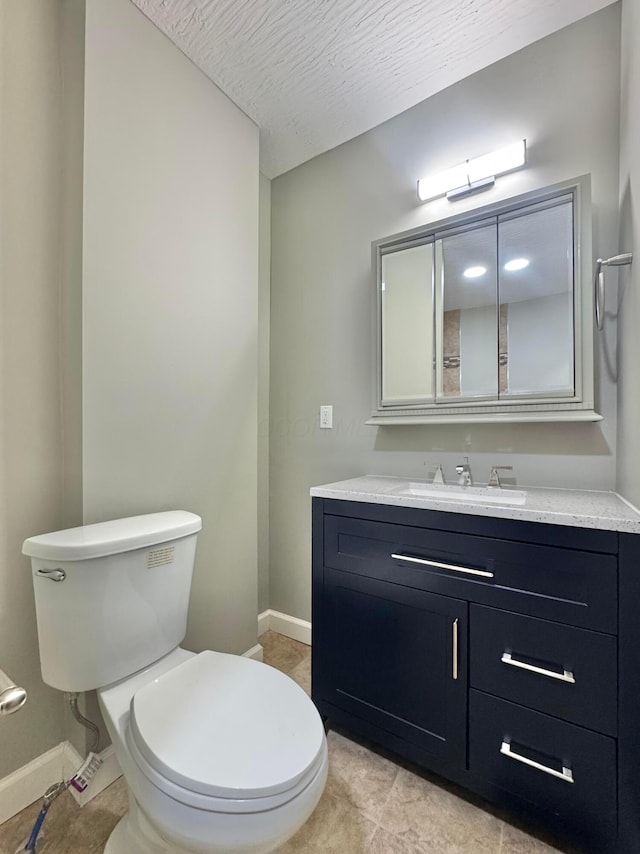 half bathroom with a textured ceiling, vanity, toilet, and baseboards