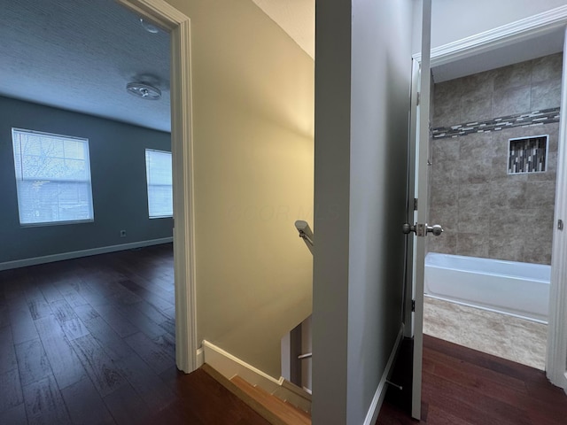 bathroom featuring a textured ceiling, shower / bathtub combination, wood finished floors, and baseboards