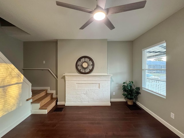 unfurnished living room featuring a ceiling fan, dark wood-style flooring, baseboards, and stairs