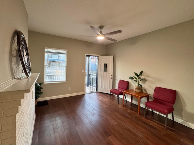 sitting room with dark wood finished floors, baseboards, and ceiling fan