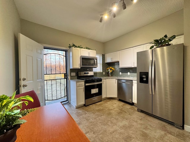 kitchen with stainless steel appliances, white cabinets, decorative backsplash, and light stone countertops