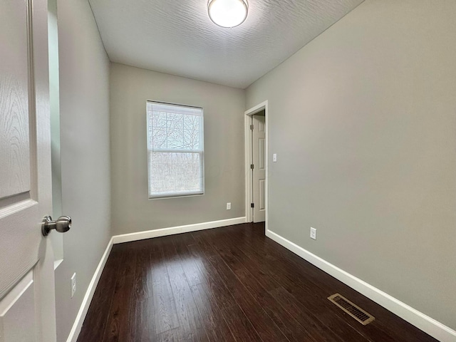 empty room featuring visible vents, a textured ceiling, baseboards, and wood finished floors