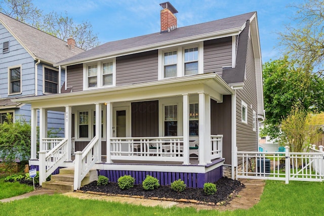 traditional style home with covered porch, a chimney, and fence