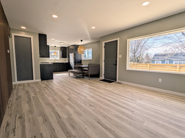 kitchen featuring light wood finished floors, recessed lighting, light countertops, and freestanding refrigerator