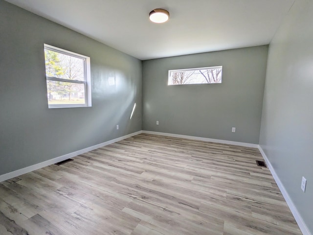 empty room featuring light wood-style floors, baseboards, and visible vents