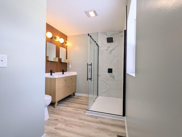 bathroom with double vanity, a marble finish shower, a sink, and wood finished floors