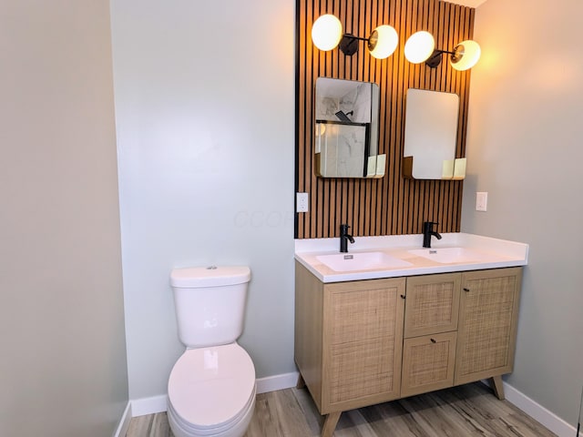 bathroom with double vanity, wood finished floors, a sink, and toilet