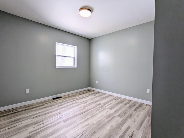 unfurnished room featuring visible vents, light wood-style flooring, and baseboards