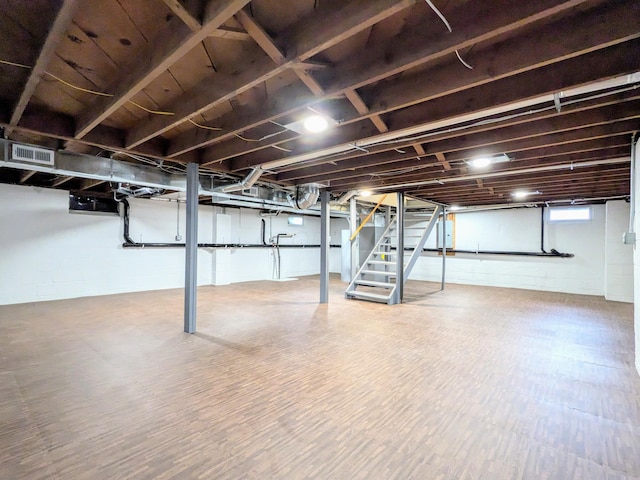 below grade area with wood finished floors, visible vents, and stairs