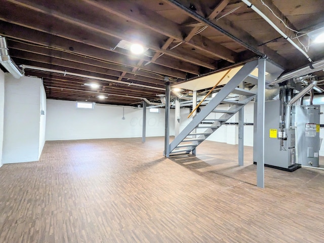 below grade area featuring electric water heater, stairway, heating unit, and wood finished floors