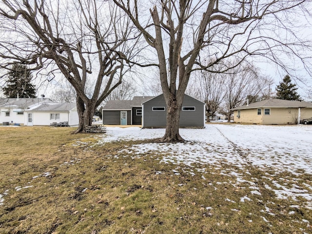 snow covered rear of property with a yard