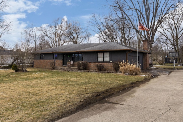 view of front of property featuring brick siding, a chimney, a front yard, a garage, and driveway