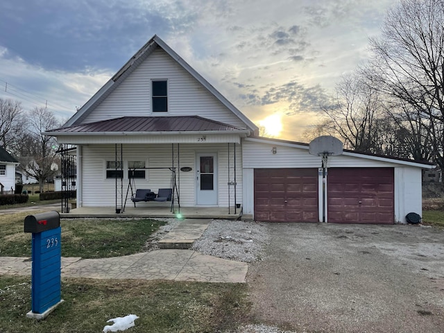 view of front of home featuring a garage, covered porch, driveway, and metal roof