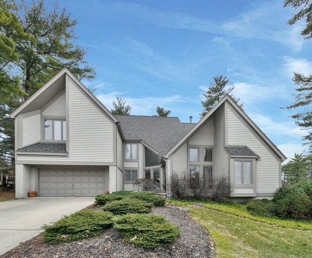 mid-century inspired home with a garage, concrete driveway, and a shingled roof