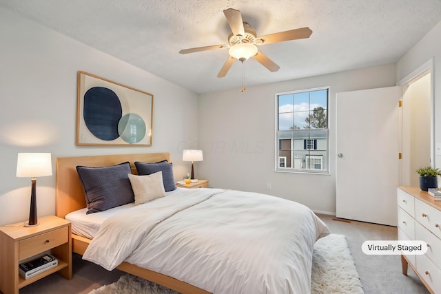 bedroom with light carpet, ceiling fan, and a textured ceiling