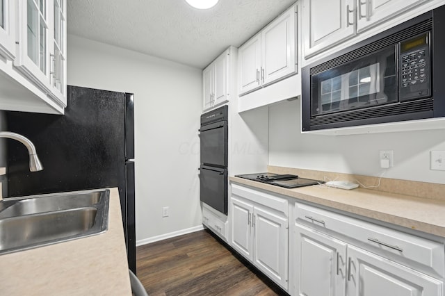 kitchen with black appliances, a sink, light countertops, and white cabinets