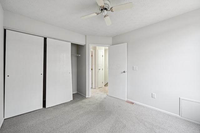 unfurnished bedroom with a textured ceiling, baseboards, a closet, and light colored carpet