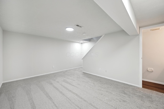 finished below grade area featuring carpet, baseboards, and visible vents