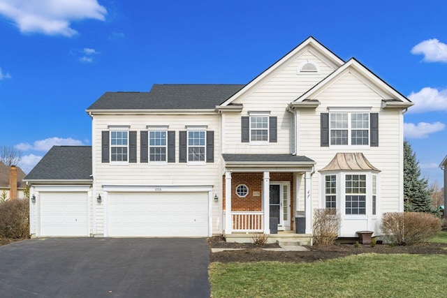 traditional-style house with aphalt driveway, a porch, an attached garage, brick siding, and a shingled roof