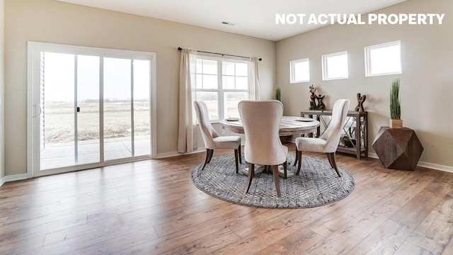 dining area featuring light wood-type flooring, visible vents, and baseboards