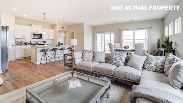 living area featuring visible vents, light wood-style flooring, and recessed lighting