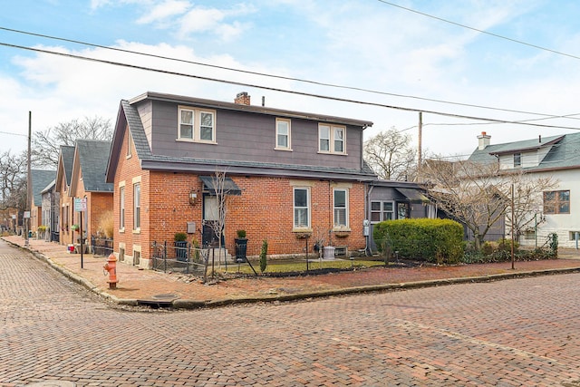 view of front of property with a fenced front yard, brick siding, and a chimney