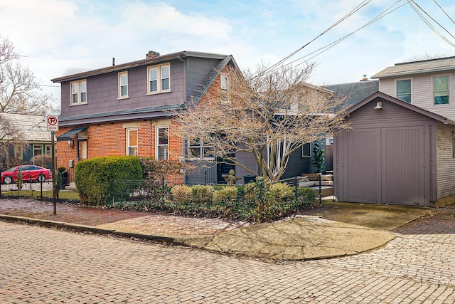 exterior space featuring an outbuilding, brick siding, fence, a shed, and a chimney