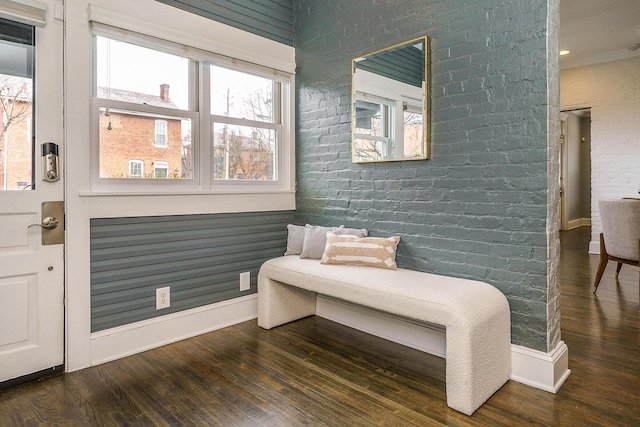 sitting room featuring baseboards, brick wall, wood finished floors, and a healthy amount of sunlight