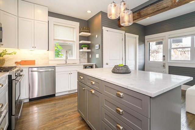 kitchen with appliances with stainless steel finishes, dark wood-style flooring, a sink, and gray cabinetry