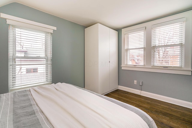 bedroom with dark wood-style floors and baseboards