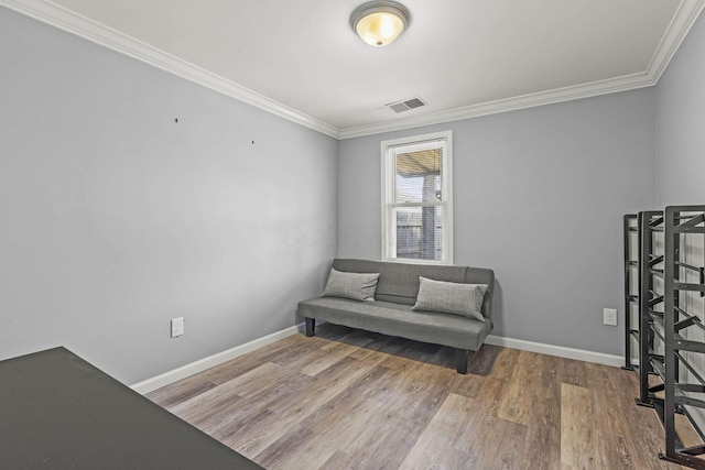 living area with baseboards, visible vents, wood finished floors, and ornamental molding