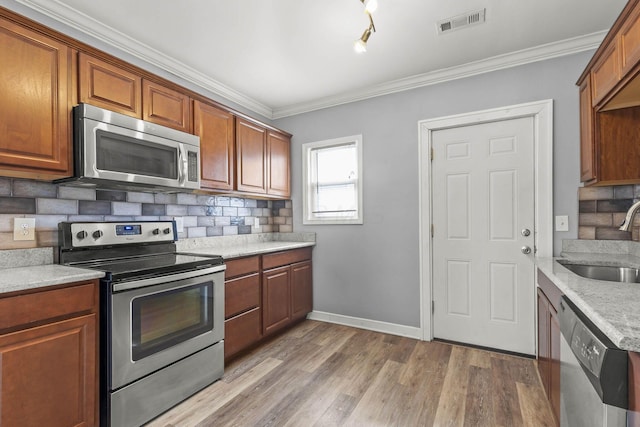 kitchen featuring a sink, visible vents, appliances with stainless steel finishes, brown cabinets, and decorative backsplash